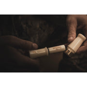 A person grips a Power Calls Beau Brooks Signature Series Duck Call in both hands, its main body and detachable end highlighted against a dim background—ideal for creating realistic mallard hen sounds.