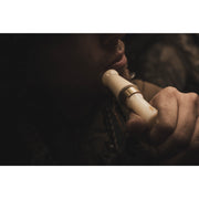 Close-up of a person using a Power Calls Beau Brooks Signature Series Duck Call, with their face partly visible and the background softly blurred.